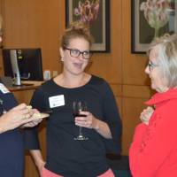 Three alumni sipping on wine and enjoying conversation